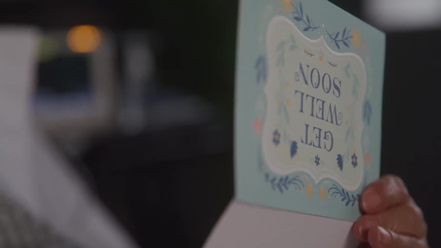 Lue card with the message get well soon is held by a hand