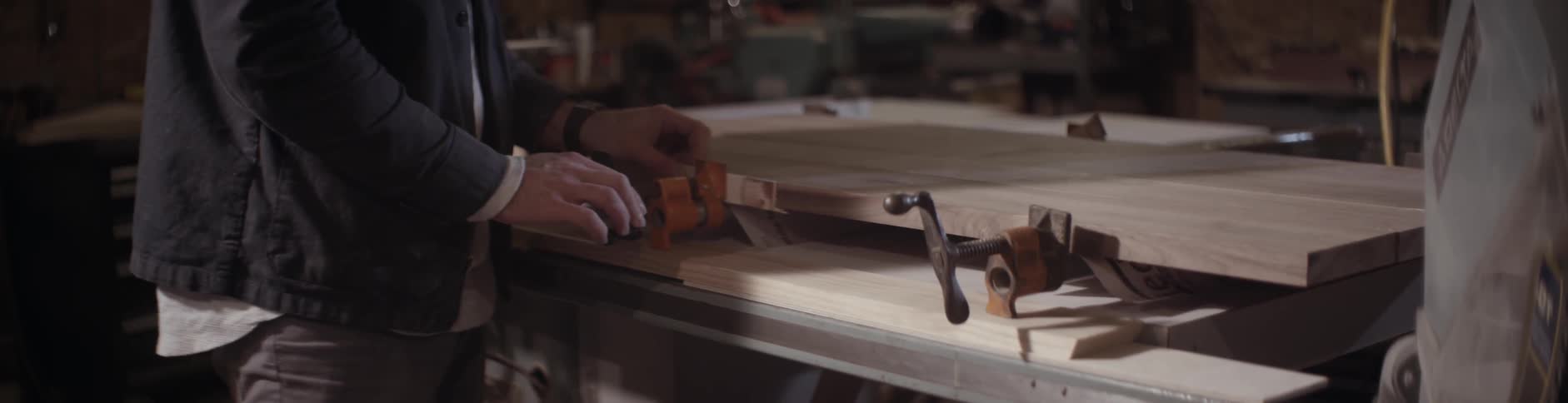 A man adjusts clamps on a slab of wood