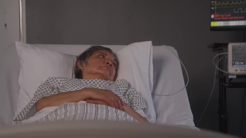 An older woman lies in a hospital bed