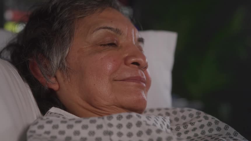 A woman lies peacefully in a hospital bed her expression calm and content