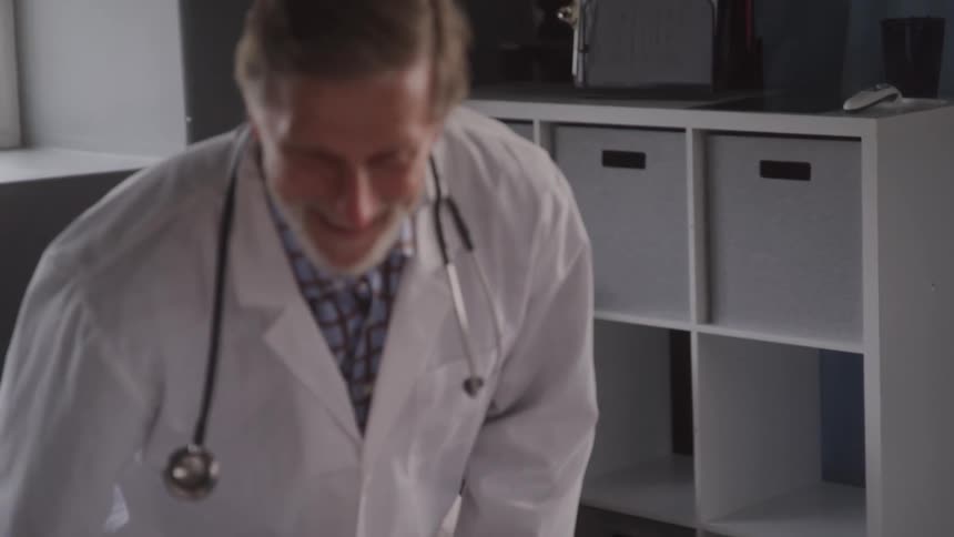The video shows a person sitting at a bedside gently holding the hand of another person who is lying in bed the person in bed is wearing a hospitalstyle gown suggesting a scene of care or comfort