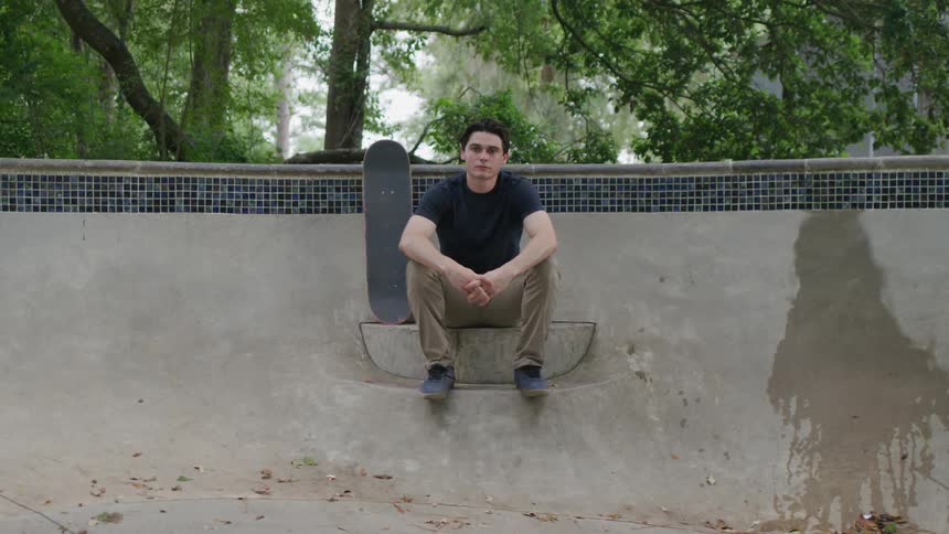 Male skateboarder sitting on a ledge inside an empty pool