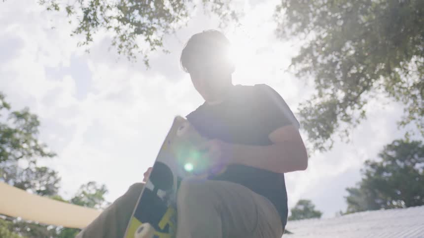 Young man adjusts skateboard outdoors