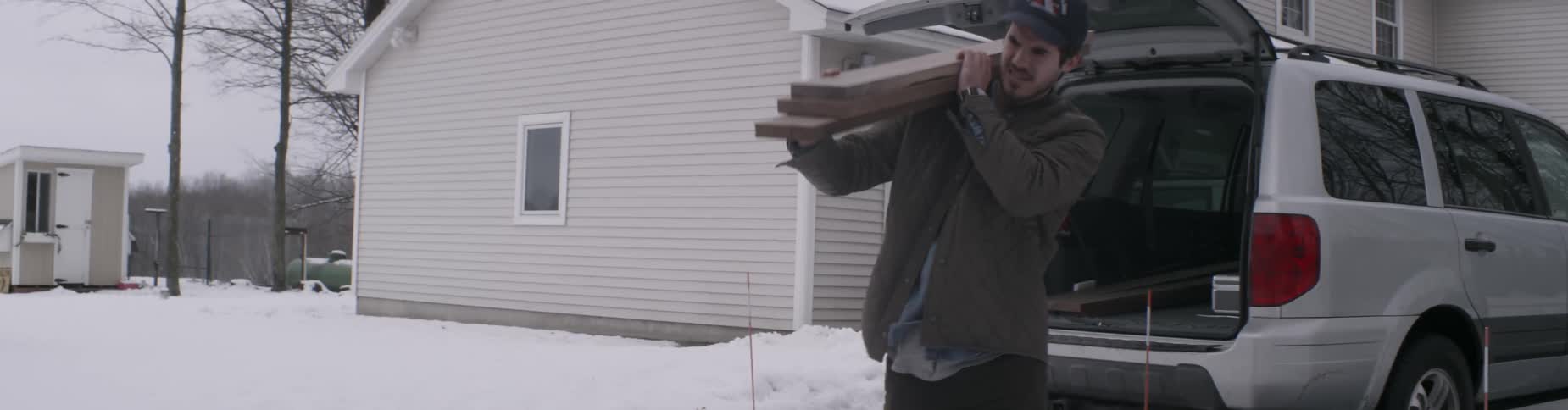 A man carries boards from a vehicle
