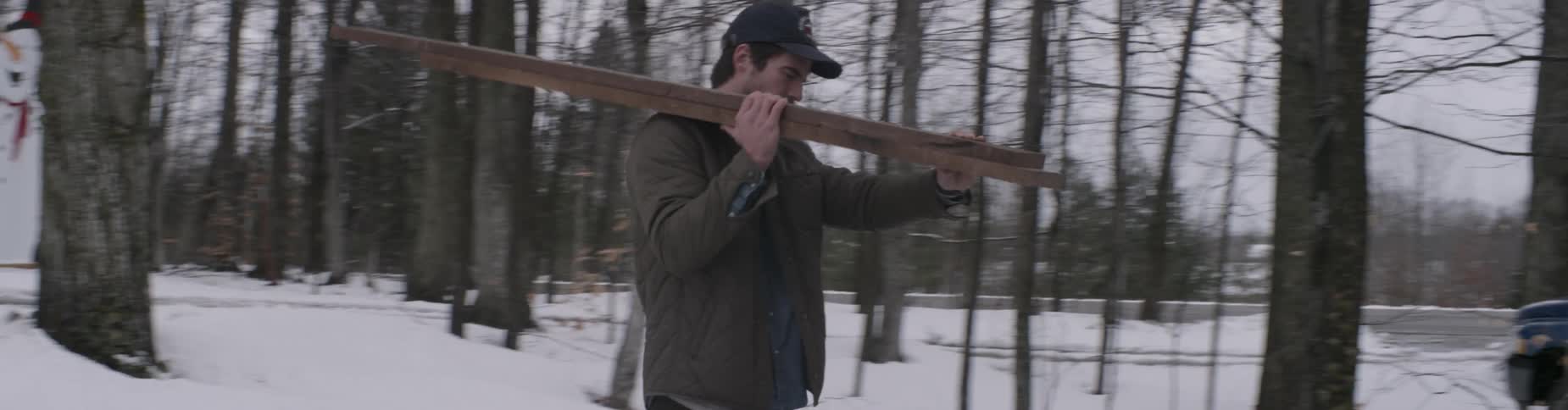 A man carries planks in the snow