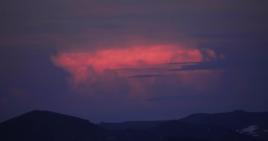 Clouds float over mountains at sunset