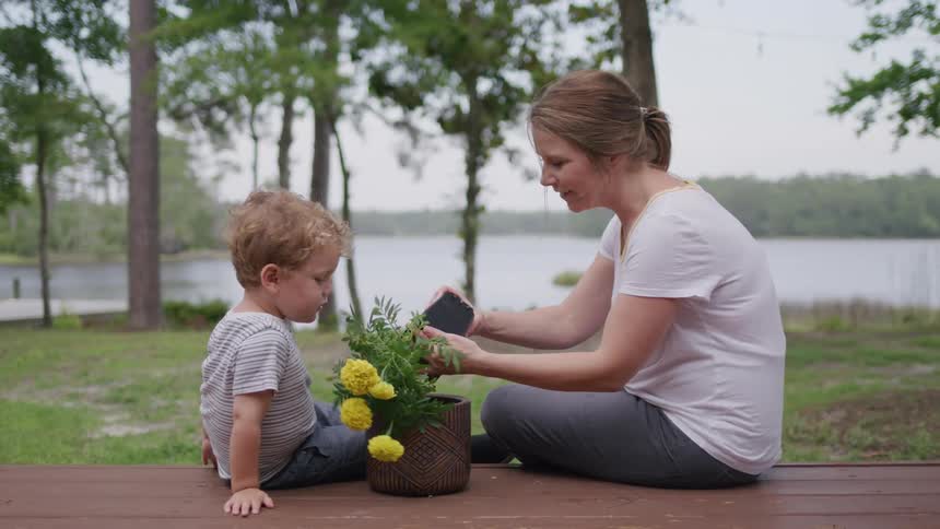 A mother teaches her son how to plant flowers