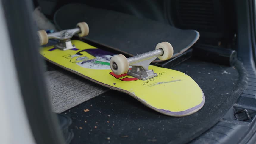 A person takes a skateboard out of their cars trunk