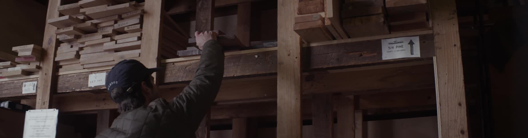 A man looks through pieces of lumber on a shelf