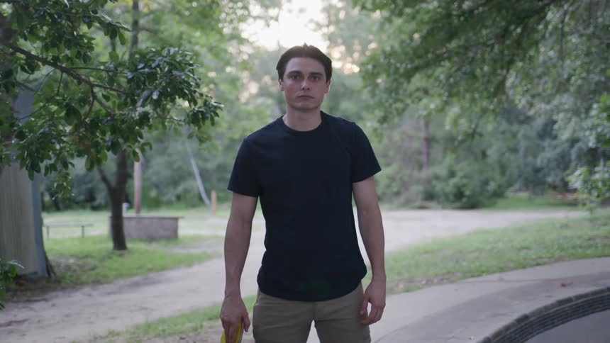A young male adult holding his skateboard while standing outdoors during daytime