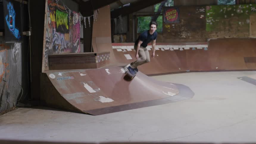 Man skateboarding in an indoor skatepark with ramps and graffiti on the walls