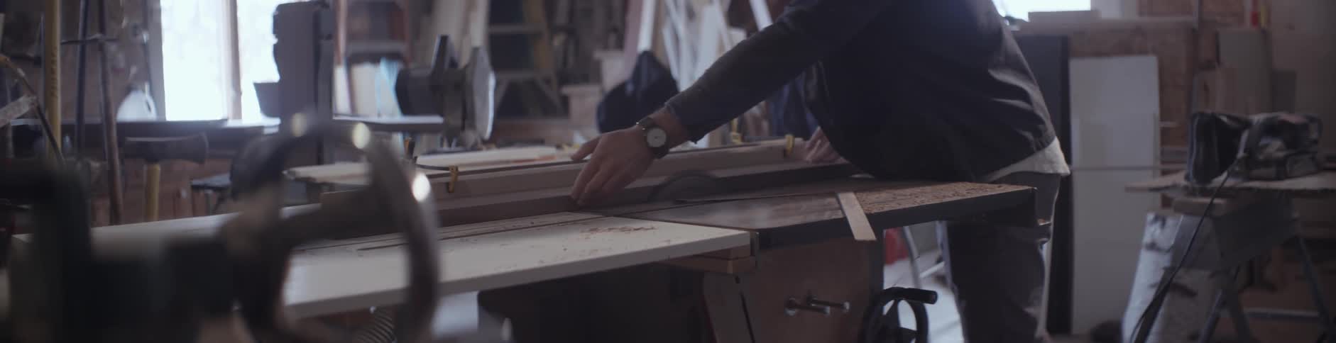 A man cuts a piece of lumber with a saw