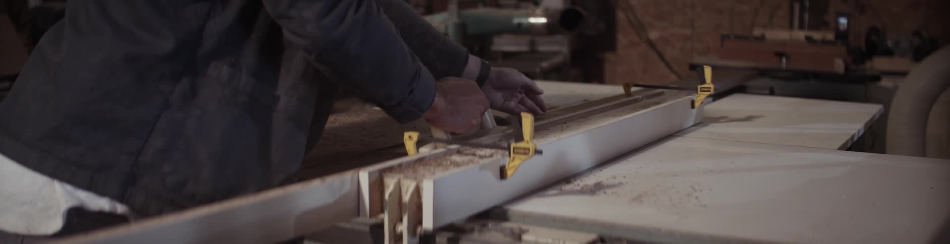 A man slides a piece of wood into a saw