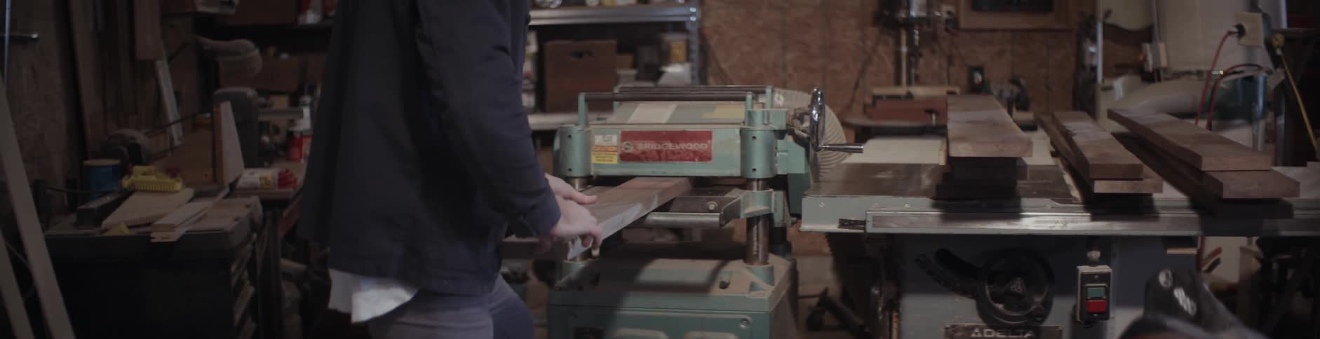 A man feeds a board through a blue machine
