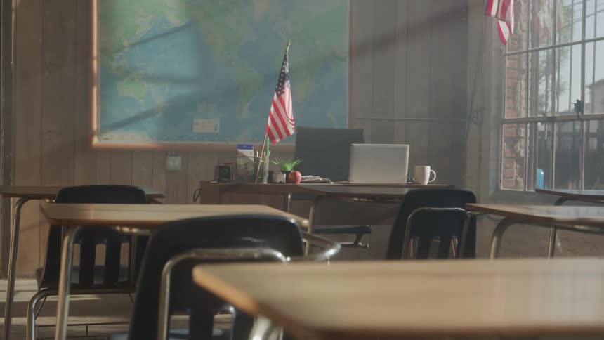 Empty classroom with desks and chairs arranged under warm natural light