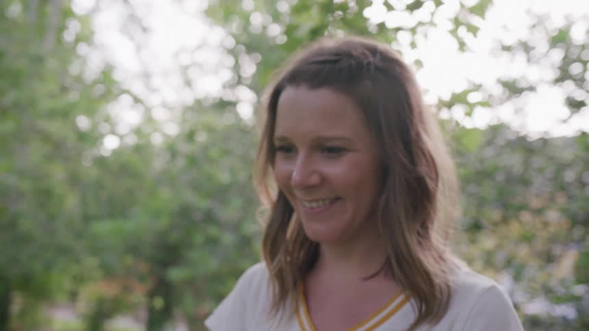 The video shows a closeup of a womans face with her head tilting slightly as she looks up she has long light brown hair that is styled with a halfbraid on top