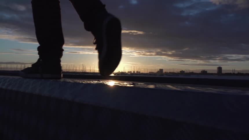 Man walks on a ledge during sunset