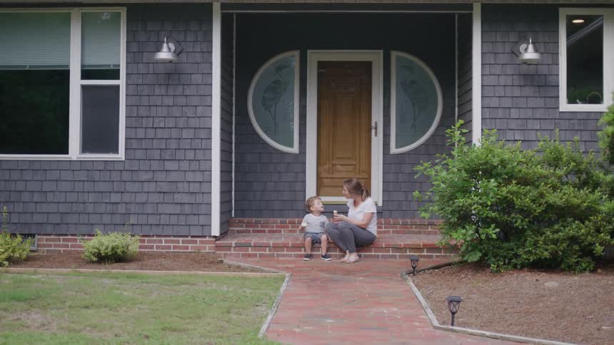 Woman sitting on the house steps talking with a young child