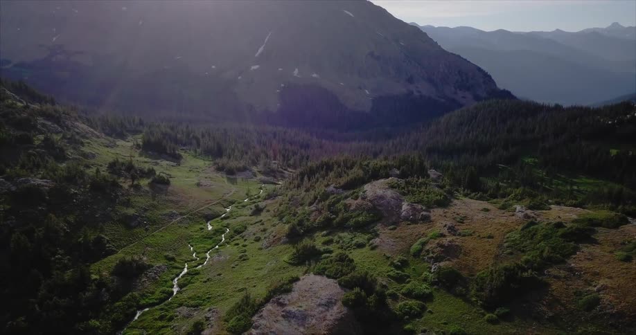The sun shines down on a valley surrounded by mountains