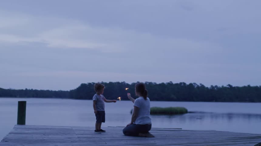 Mother with her young son on a seaside pier holding a lit candle