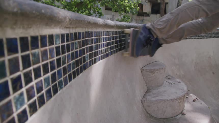 Person skates along the curved edge of a tiled concrete structure