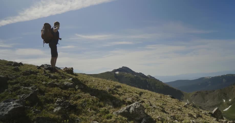 A hiker sits down on a rocky hillside