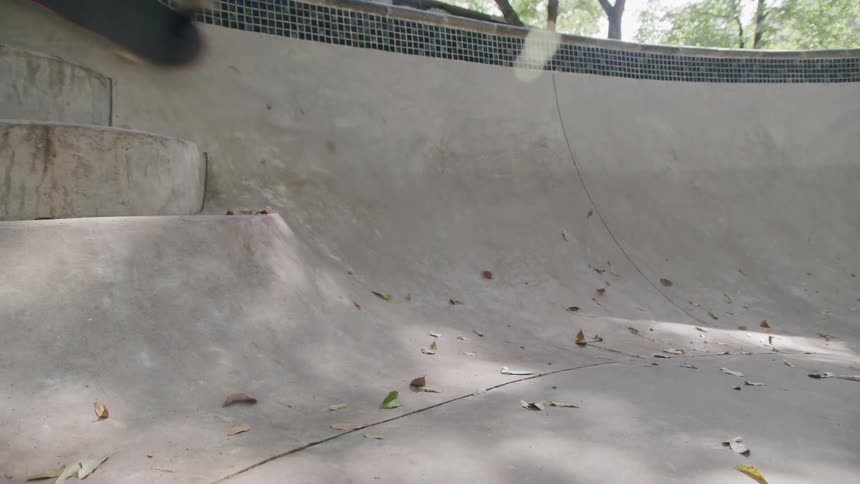 The video shows a closeup of the concrete surface of a skate bowl the surface is smooth and curved with a tiled edge visible at the top