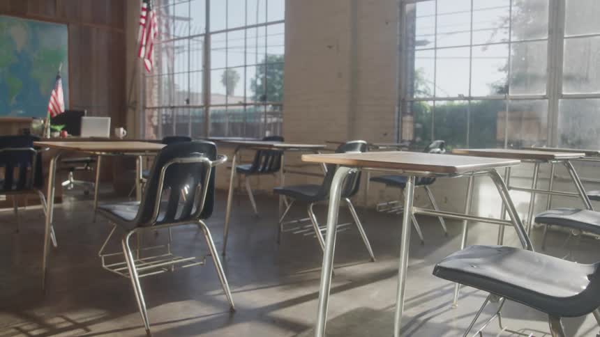 Empty classroom with desks lined up beside bright windows