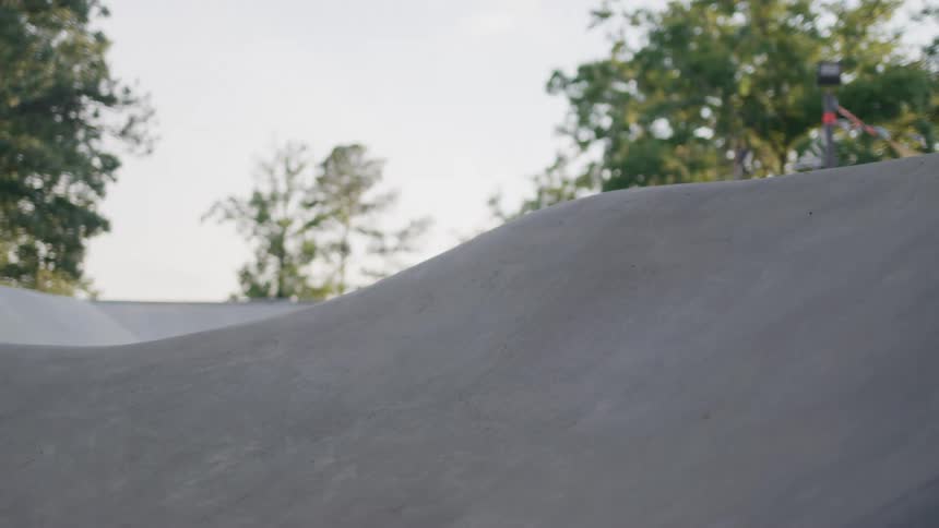 A closeup shot of a person skateboarding on a smooth grey ramp the skater rides past the camera and then disappears from the frame