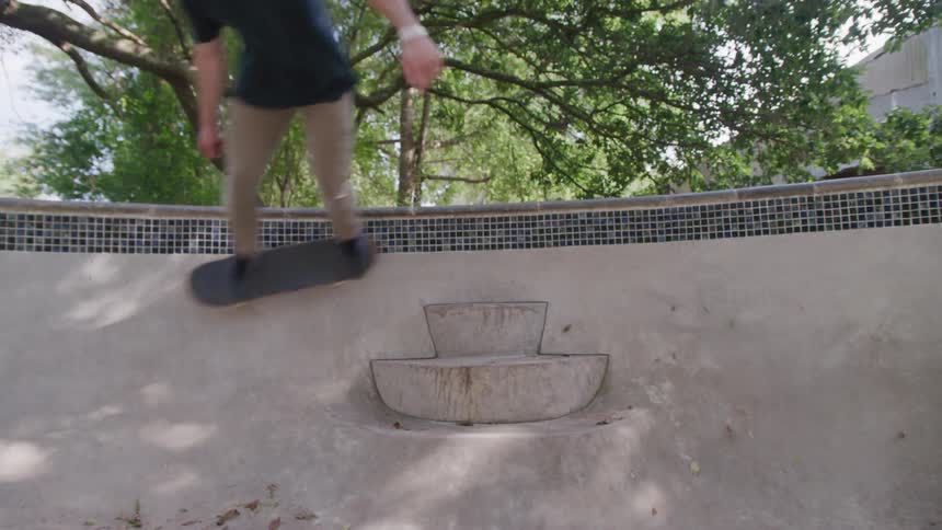The teenager is skateboarding in the empty pool