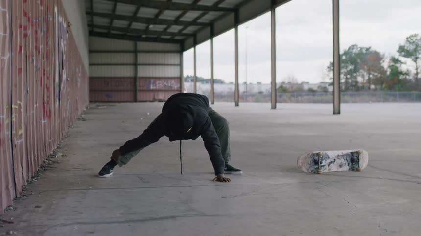 A man stretching near a skateboard