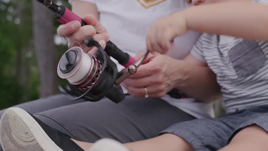 Woman and child holding a pink fishing rod together
