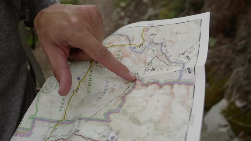 A finger points at a spot on a map