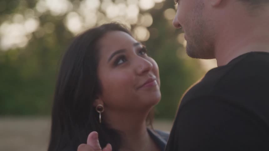 Woman gazes tenderly at the man as they share a close moment outdoors