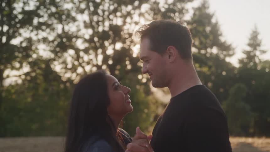 Couple dancing outdoors as the man kisses the womans forehead under the sunset light