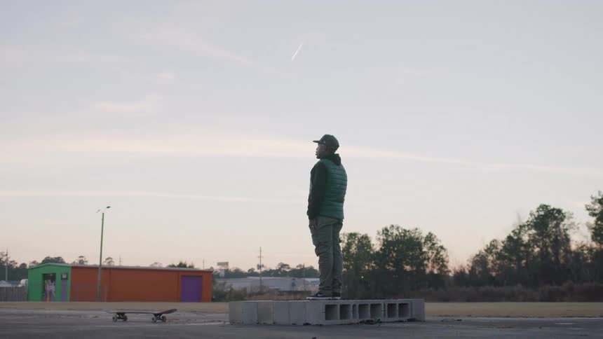 A young black male stands on an arrangement of concrete blocks outdoors during daytime