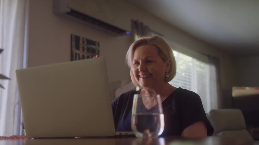 Woman smiles while talking on a video call on her laptop