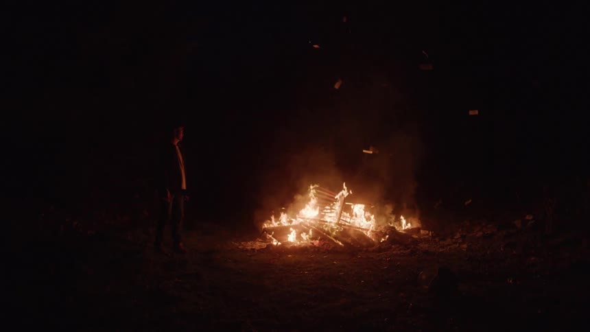 A man watches furniture burn at night