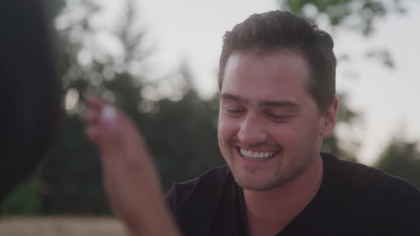 Man smiles while talking with a woman outdoors