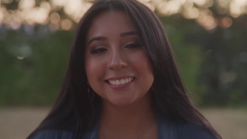 Woman smiling outdoors with a blurred background