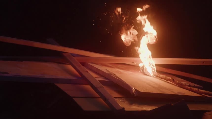 Flames consume stacked pieces of wood in the dark