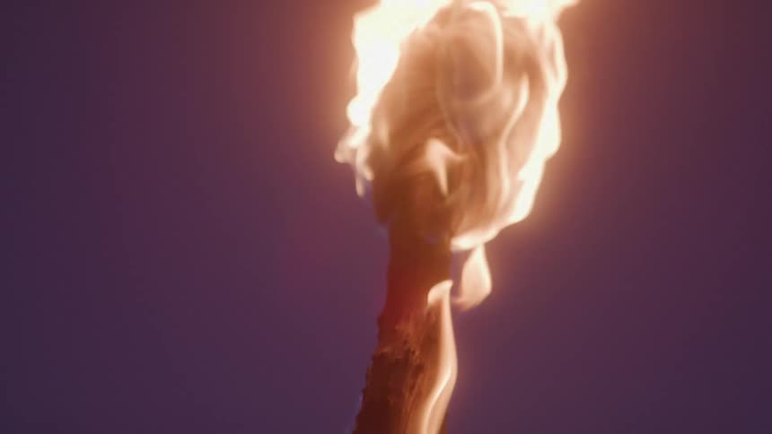 A burning torch glows brightly against the deep blue evening sky