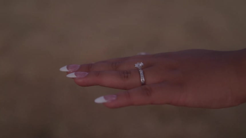 Hand with french manicure displays a silver engagement ring