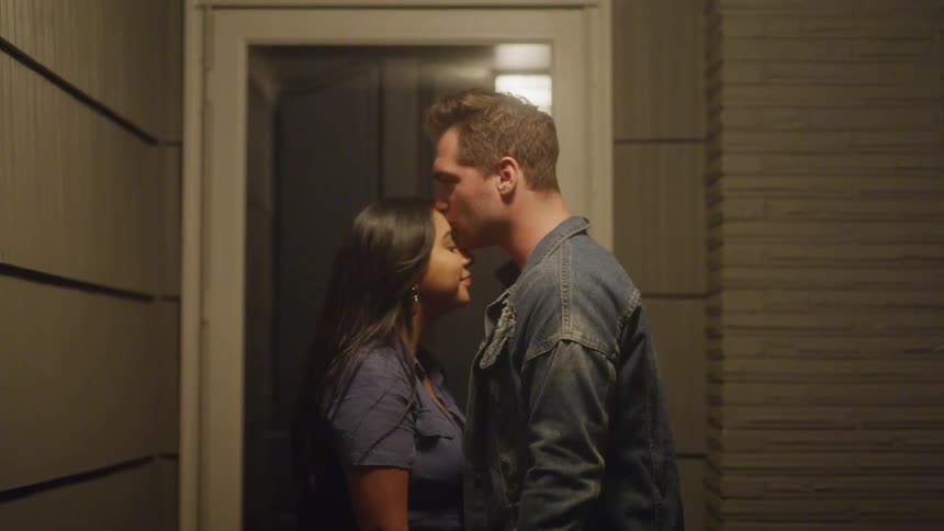 Man kisses a womans forehead in front of a lit doorway