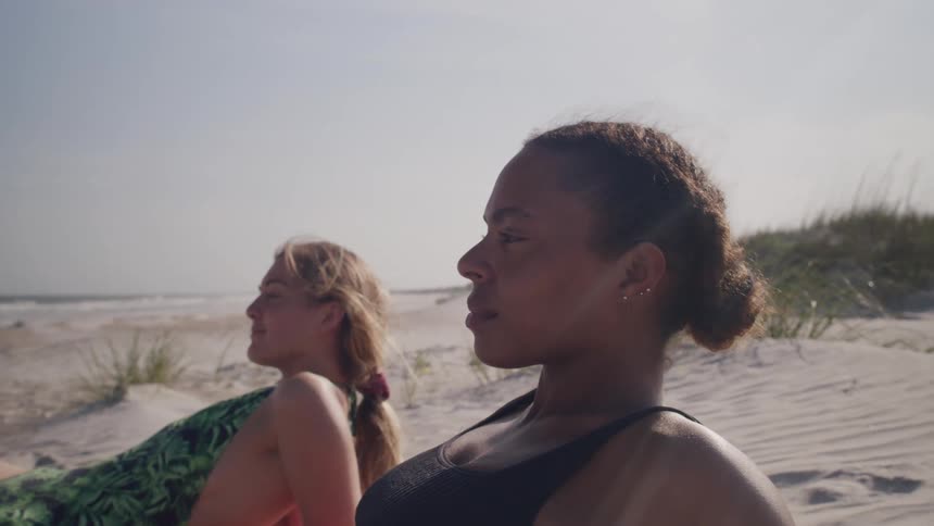 Women in swimsuits lie on the sand watching the sea