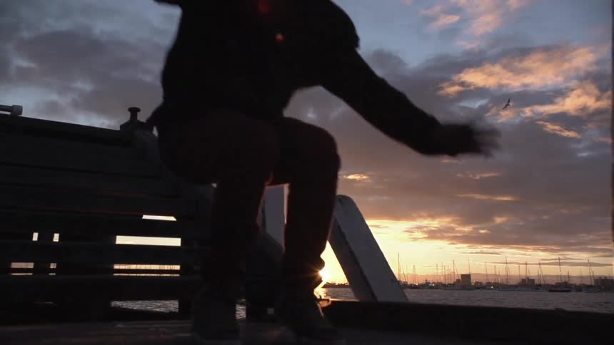 A man jumps down some steps at sunset