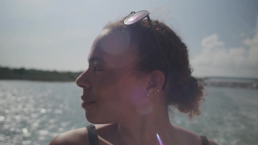 A woman puts sunglasses on her head during a boat ride in the ocean at midday