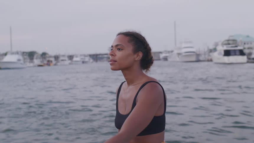 A woman is standing in the water looking around at the boats