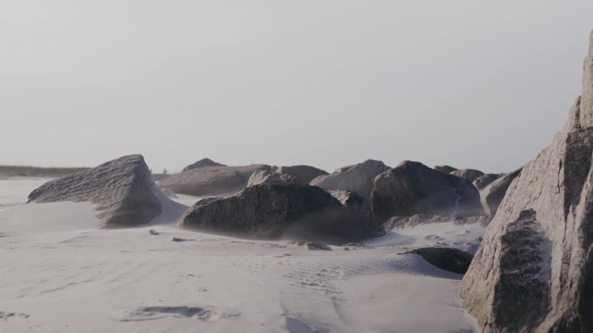 Large rocks scattered over light sand on a deserted beach