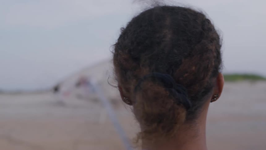 Woman in profile with tied hair looks at the horizon outdoors